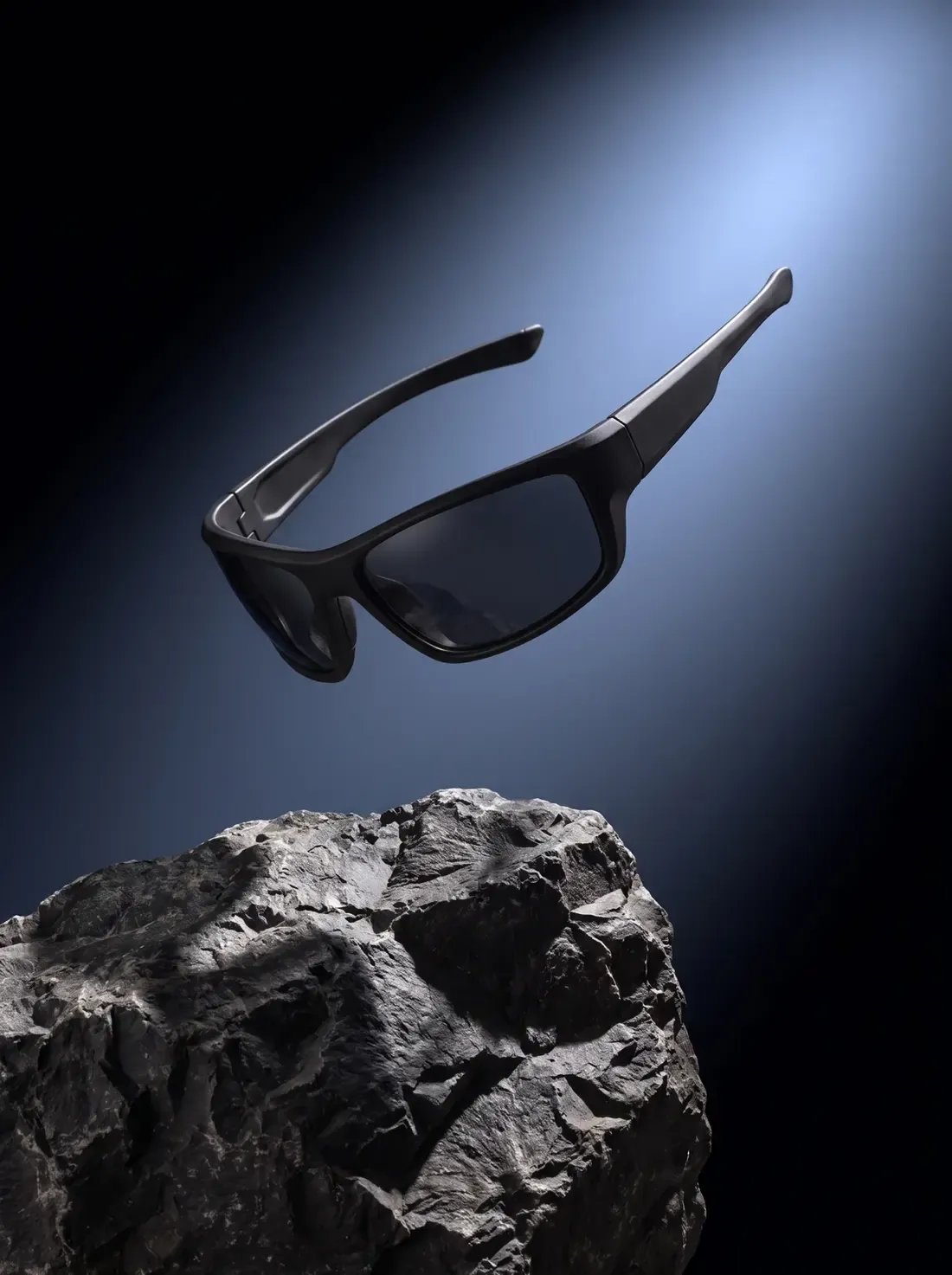 The Halden frame, matte black, suspended in a hard blue spotlight above a slab of rock.